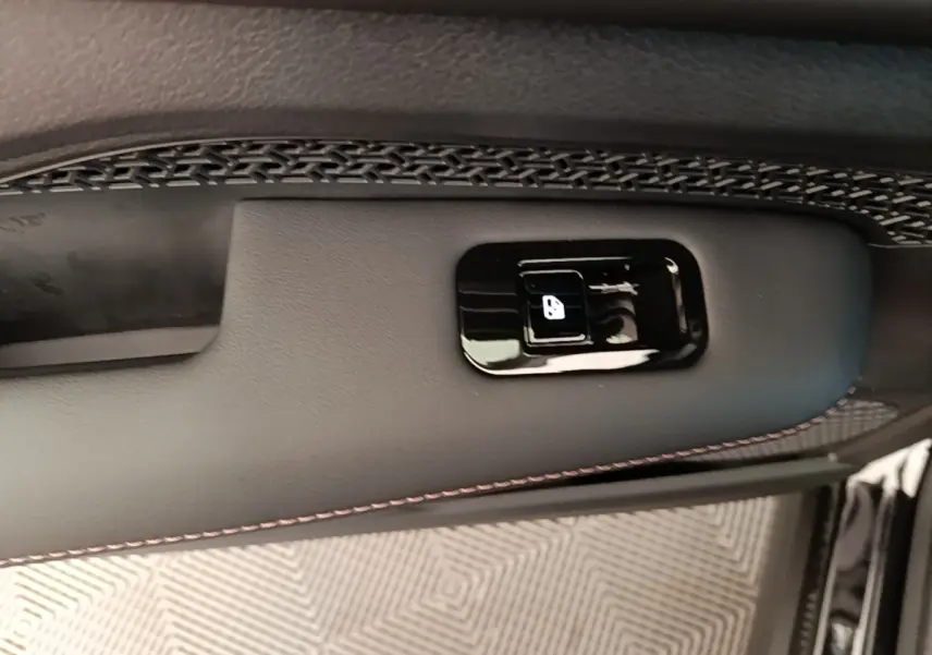 Détail du bouton d’ouverture de trappe à carburant sur la porte intérieure noire du Nissan Ariya 2026.