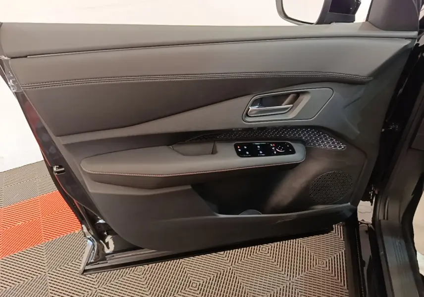 Vue rapprochée de la porte avant gauche noire du Nissan Ariya 63kWh 218ch Engage avec commandes électriques et haut-parleur intégré.