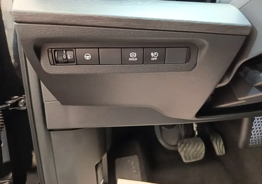 Vue intérieure côté conducteur du Nissan Ariya noir 2026, avec commandes d'assistance et pédales visibles.