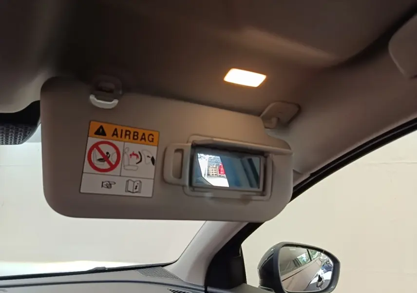 Détail intérieur du pare-soleil côté conducteur avec miroir et éclairage allumé dans un Nissan Ariya noir.