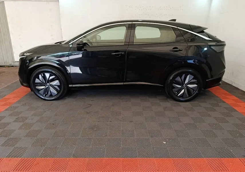 Vue de profil côté gauche du Nissan Ariya noir 63kWh 218ch Engage avec jantes stylisées et lignes épurées.