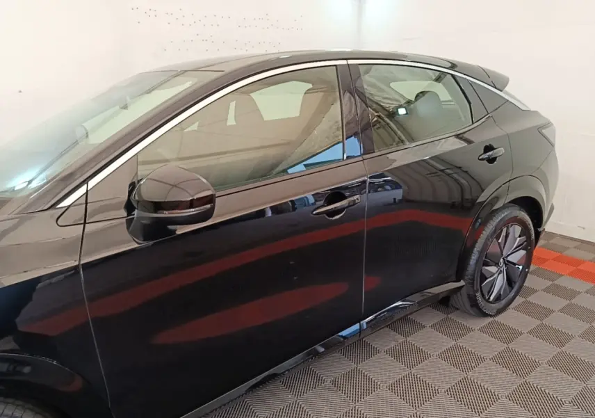 Vue latérale côté gauche d'un Nissan Ariya noir 63kWh 218ch Engage avec jantes modernes et rétroviseur assorti.