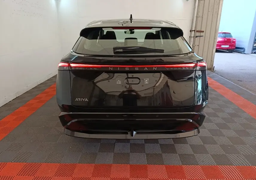 Vue arrière d'un Nissan Ariya noir 2026 avec feux arrière LED continus et logo Nissan lumineux.