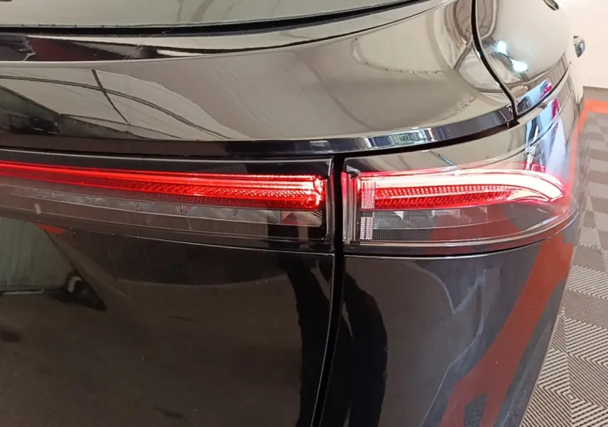 Gros plan sur le feu arrière droit rouge du Nissan Ariya noir, soulignant la finition lisse et brillante.