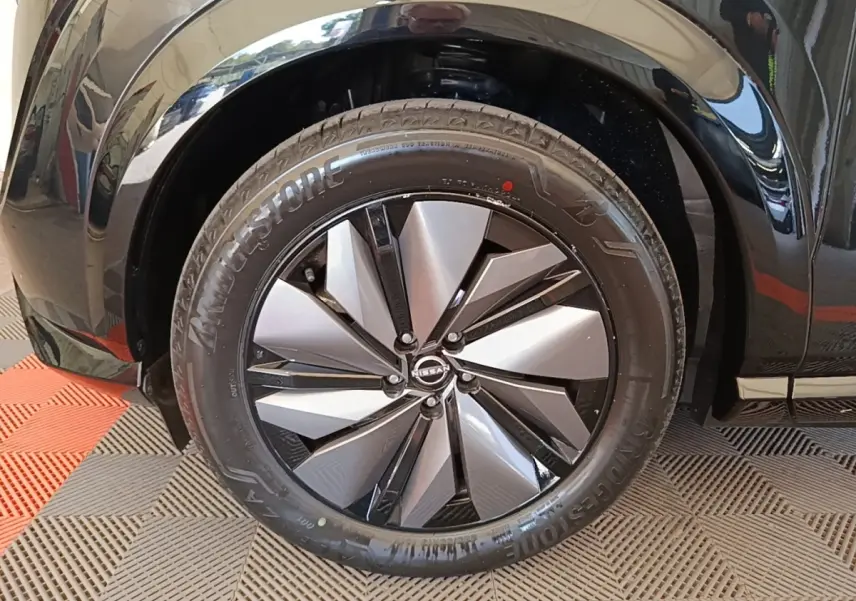Gros plan sur la roue avant droite noire du Nissan Ariya 63kWh 218ch Engage avec jante design bicolore.