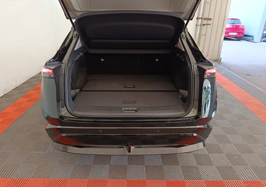 Vue arrière du coffre ouvert du Nissan Ariya noir 63kWh 218ch Engage, montrant l'espace de chargement plat.