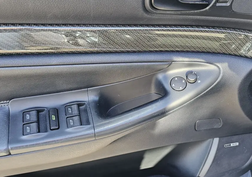 Gros plan sur la porte avant gauche de l'Audi RS4 Avant grise, montrant les commandes des vitres et le revêtement carbone.