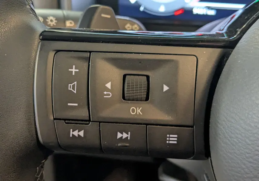 Gros plan sur les commandes multifonctions noires à gauche du volant du Nissan Qashqai blanc 2024.