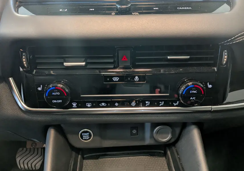 Vue rapprochée du tableau de bord noir du Nissan Qashqai 2024, mettant en valeur la climatisation automatique et le bouton start/stop.