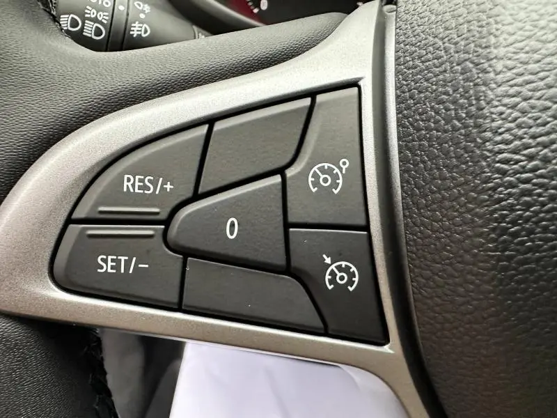 Gros plan sur les commandes de régulateur de vitesse sur le volant noir du Dacia Jogger gris Schiste 2024.