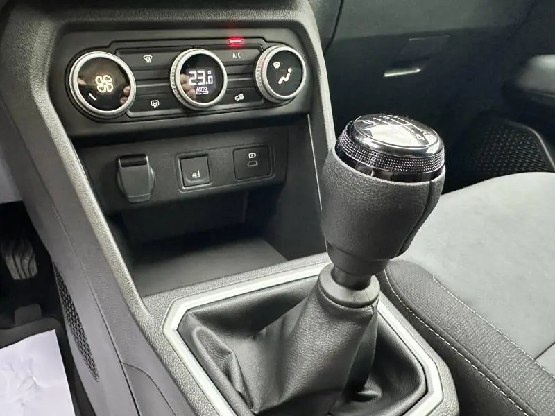 Gros plan sur la commande de boîte manuelle et la console centrale noire du Dacia Jogger 2024 avec climatisation digitale.
