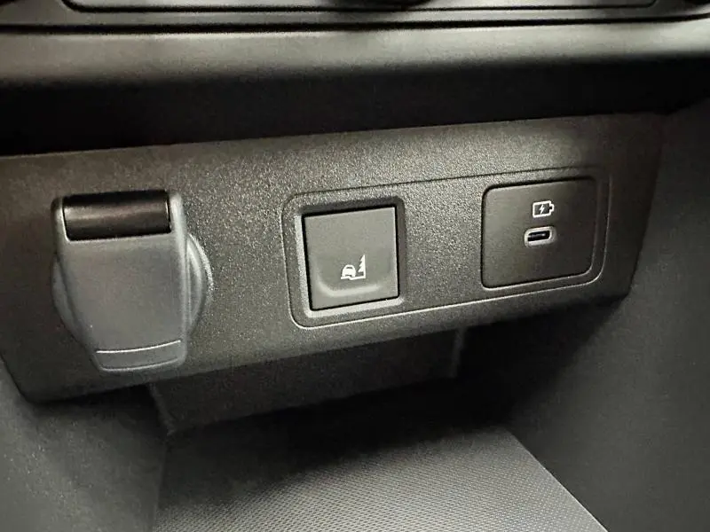 Vue rapprochée des commandes noires de la console centrale du Dacia Jogger 2024, avec prises USB et fonction aide au démarrage en côte.