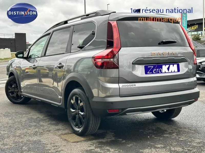 Vue 3/4 arrière droite du Dacia Jogger gris schiste métallisé avec jantes noires et barres de toit visibles.