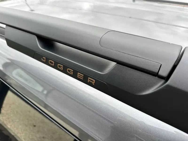 Gros plan sur la poignée arrière noire avec lettrage Jogger cuivré sur carrosserie gris schiste métallisé.