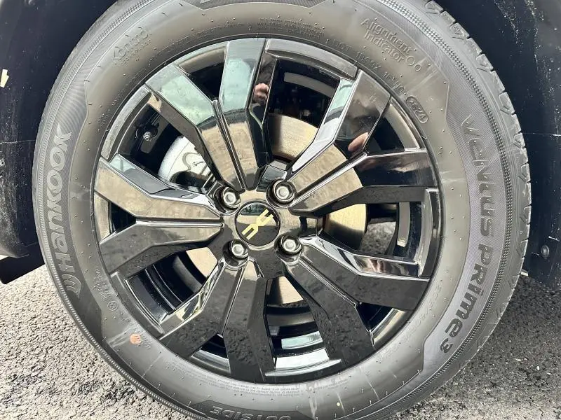 Gros plan sur la jante noire brillante avec logo électrique jaune du Dacia Jogger Gris Schiste métallisé.