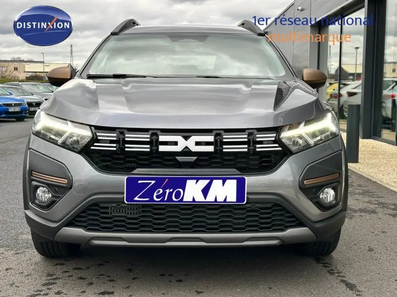 Vue frontale d'un Dacia Jogger gris schiste métallisé avec phares LED allumés et calandre noire distinctive.