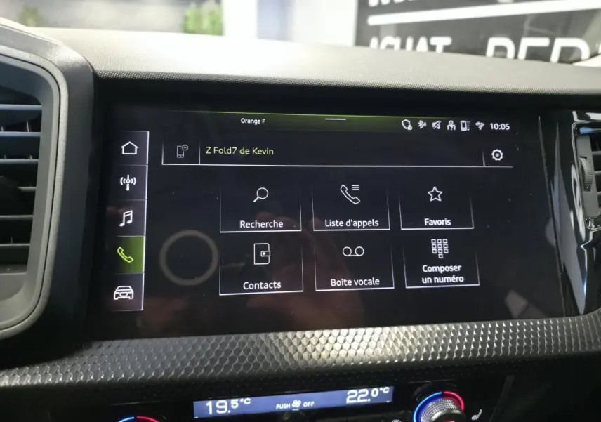 Écran tactile central de l’Audi A1 Sportback 2024 avec interface téléphone, entouré de décorations noires à motifs polygonaux.