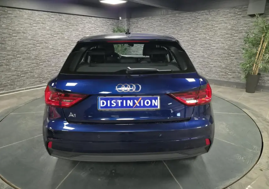 Vue arrière d'une Audi A1 Sportback 2024 bleu métallisé avec feux LED et logo distinctif sur fond intérieur gris.