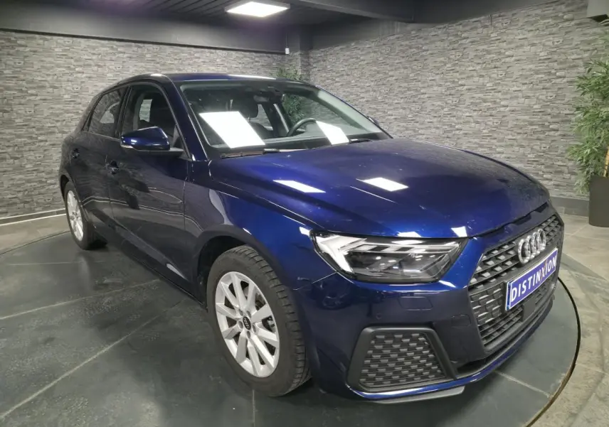 Audi A1 Sportback bleu métallisé vue 3/4 avant droit avec calandre noire et jantes alu 16 pouces dans un showroom.