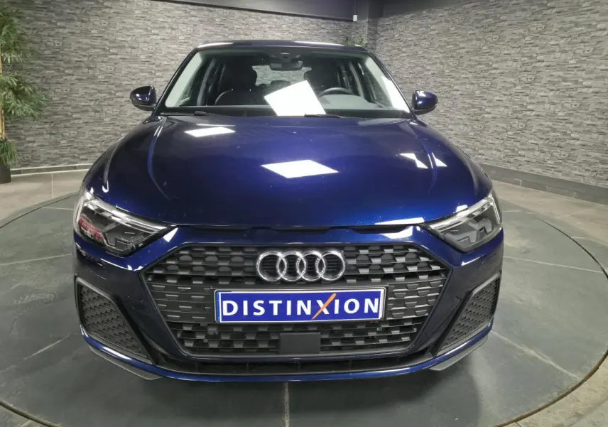 Vue frontale d'une Audi A1 Sportback 2024 bleu métallisé avec calandre noire et phares LED anguleux.