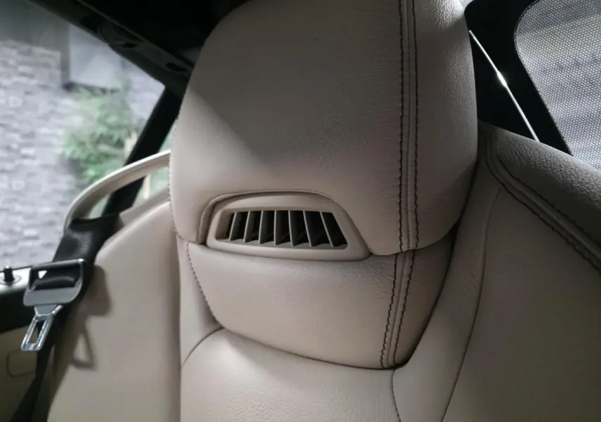 Gros plan sur l'appuie-tête en cuir beige avec sortie d'air intégrée du siège avant d'une Mercedes SLK gris 2012.
