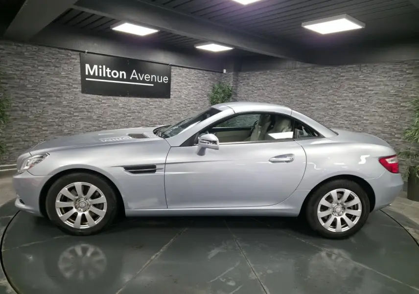 Profil côté gauche d'une Mercedes SLK 250 CDI gris métallisé avec toit rigide et sellerie cuir beige visible.