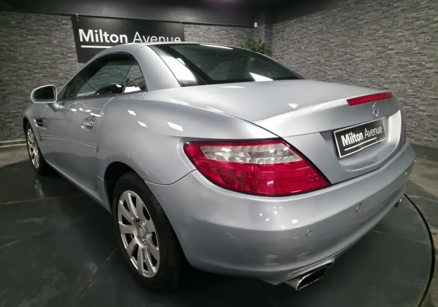 Vue 3/4 arrière droite d'une Mercedes SLK gris métallisé avec feux arrière LED et double sortie d'échappement chromée.