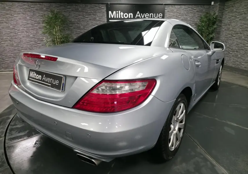 Vue 3/4 arrière droite d'une Mercedes SLK gris métallisé avec feux arrière LED et échappement double chromé.