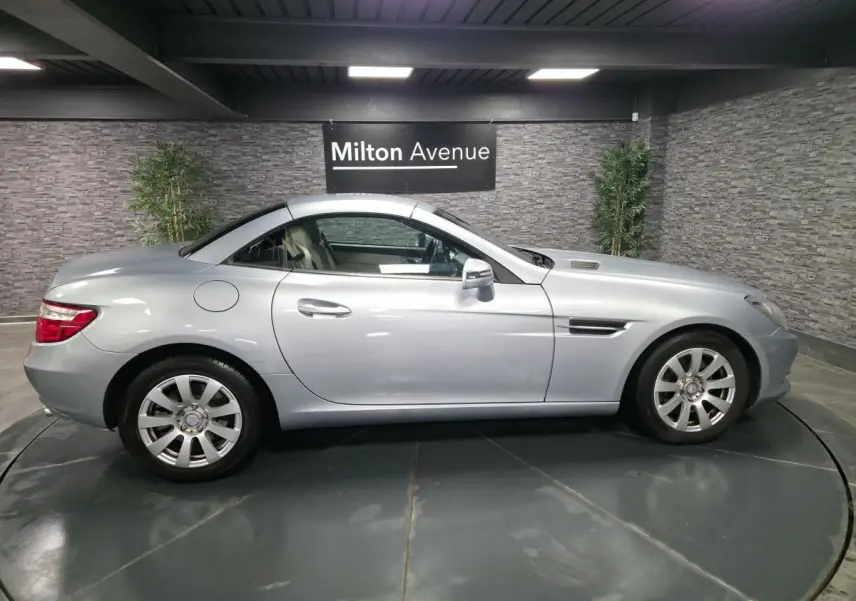 Mercedes SLK gris métallisé vue de profil côté gauche, toit rigide escamotable fermé, jantes alliage 16 pouces.