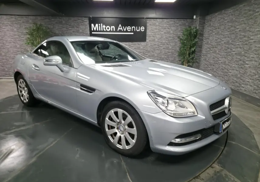 Mercedes SLK 250 CDI gris métallisé vue 3/4 avant droit avec jantes alliage et toit fermé dans un showroom.