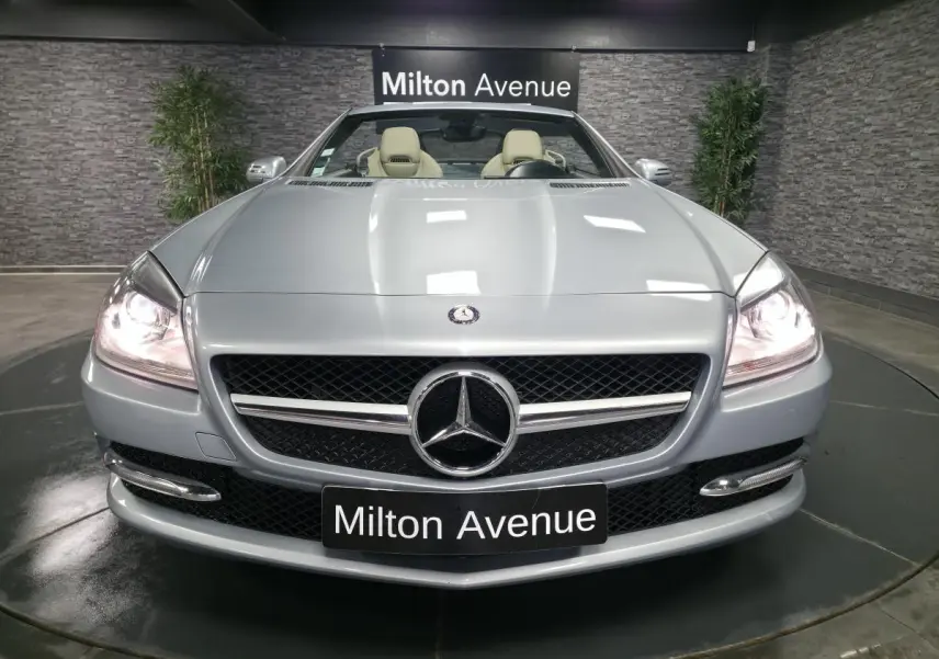 Vue avant d'une Mercedes SLK 250 CDI gris métallisé avec phares allumés et sellerie cuir beige visible