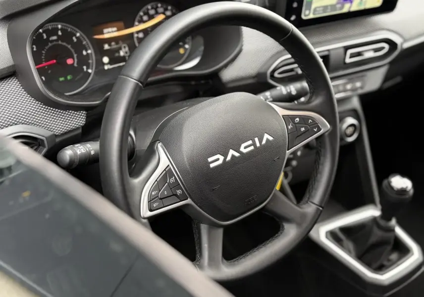 Vue rapprochée de l'intérieur du Dacia Jogger 2025, volant noir avec commandes et levier de vitesses manuel visible.