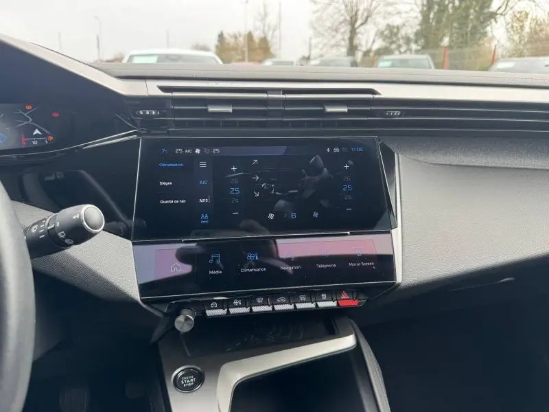 Vue intérieure du tableau de bord de la Peugeot 308 2024, écran tactile central avec commandes climatisation et multimédia.