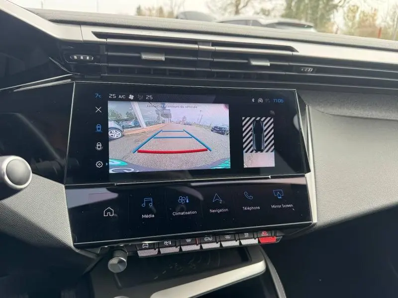 Vue rapprochée de l'écran central du Peugeot 308 2024 montrant la caméra de recul et les commandes tactiles en noir brillant.