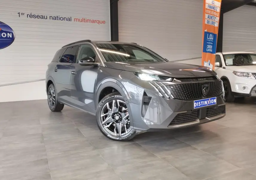 Peugeot 5008 gris titanium en 3/4 avant droit, avec calandre noire et jantes alliage 19 pouces diamantées.