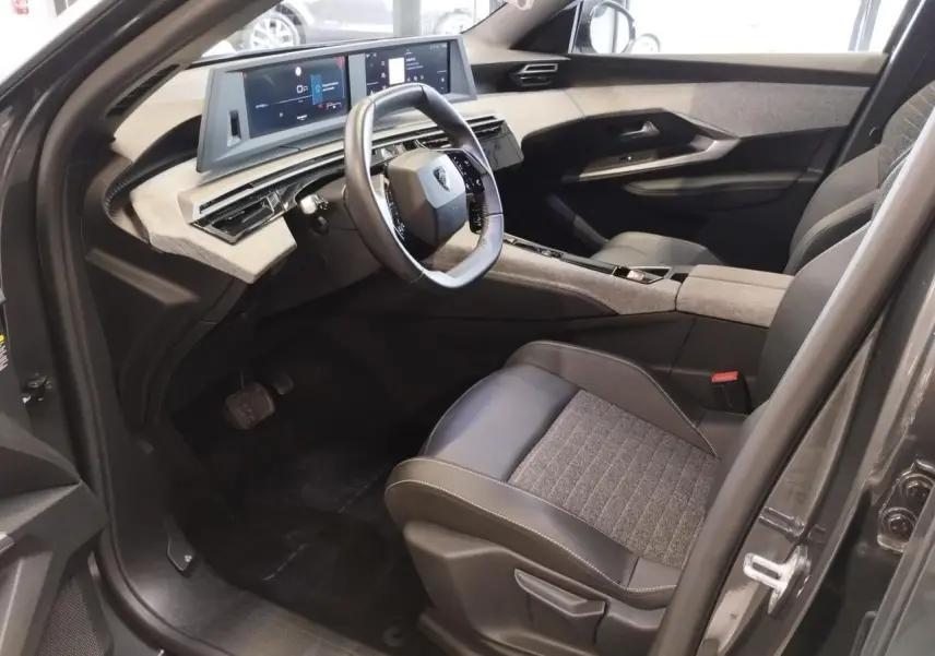 Intérieur avant droit du Peugeot 5008 gris titanium 2025 avec tableau de bord numérique et sellerie tissu cuir.