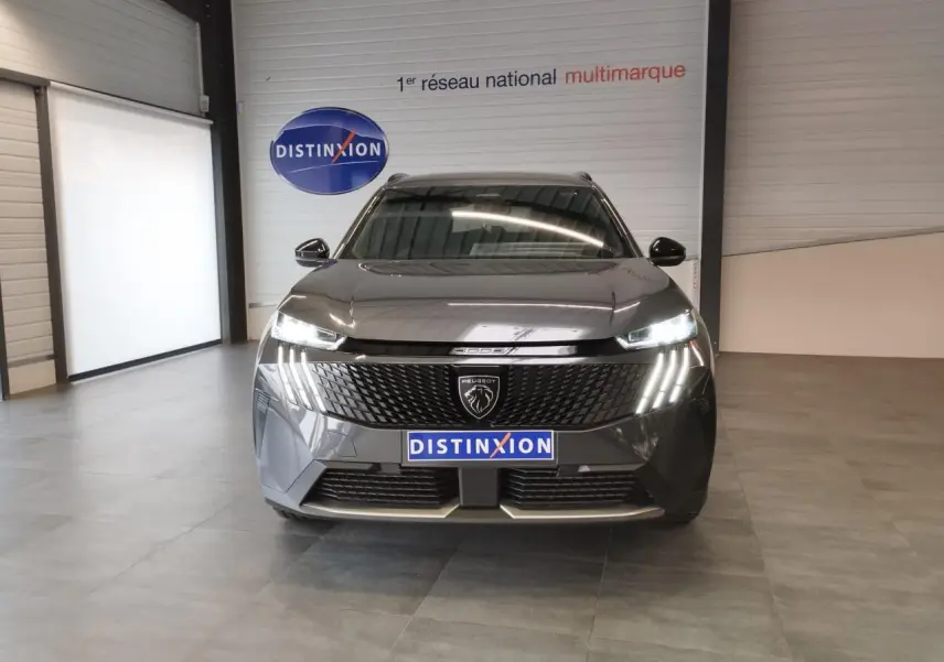 Vue frontale du Peugeot 5008 gris titanium 2025 avec feux LED allumés et calandre noire laquée.