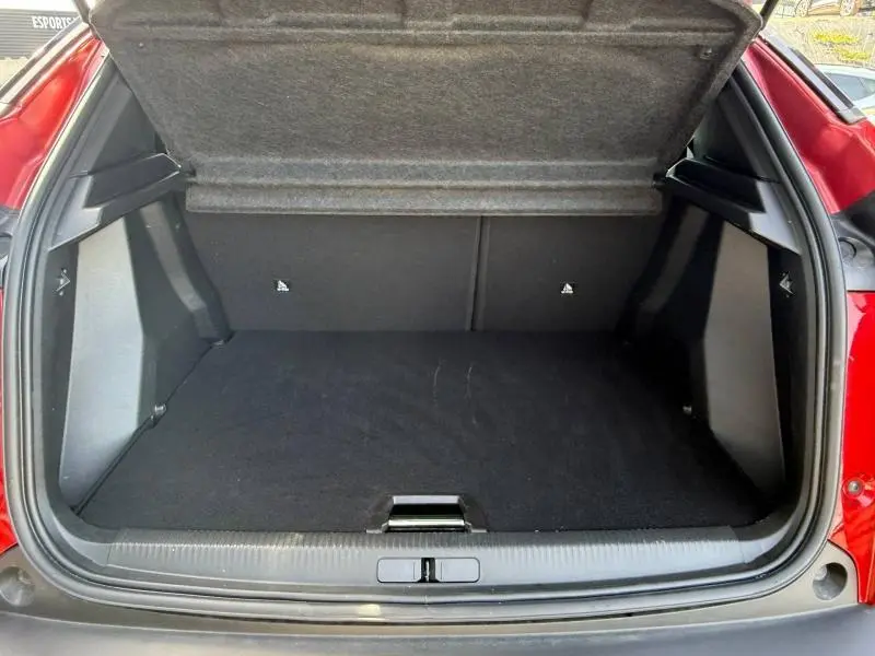 Coffre ouvert vu de l'arrière d'un Peugeot 2008 2025 Rouge Elixir, montrant un espace de chargement propre et spacieux.