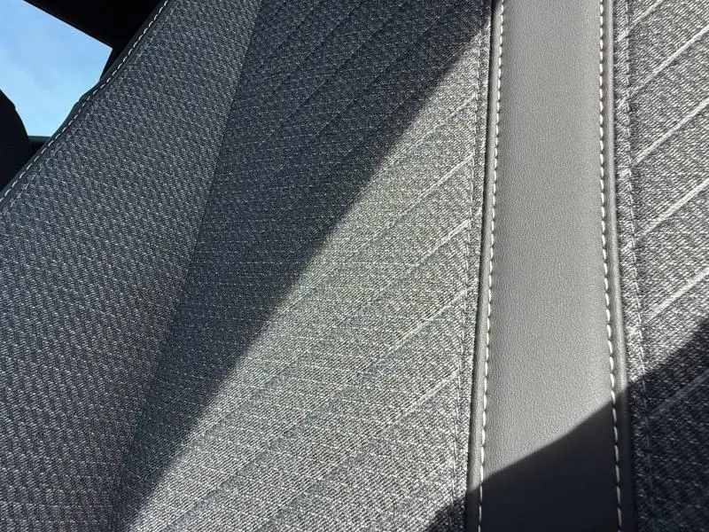 Détail du tissu gris texturé et surpiqûres blanches sur la sellerie intérieure du Peugeot 2008 Rouge Elixir 2025.