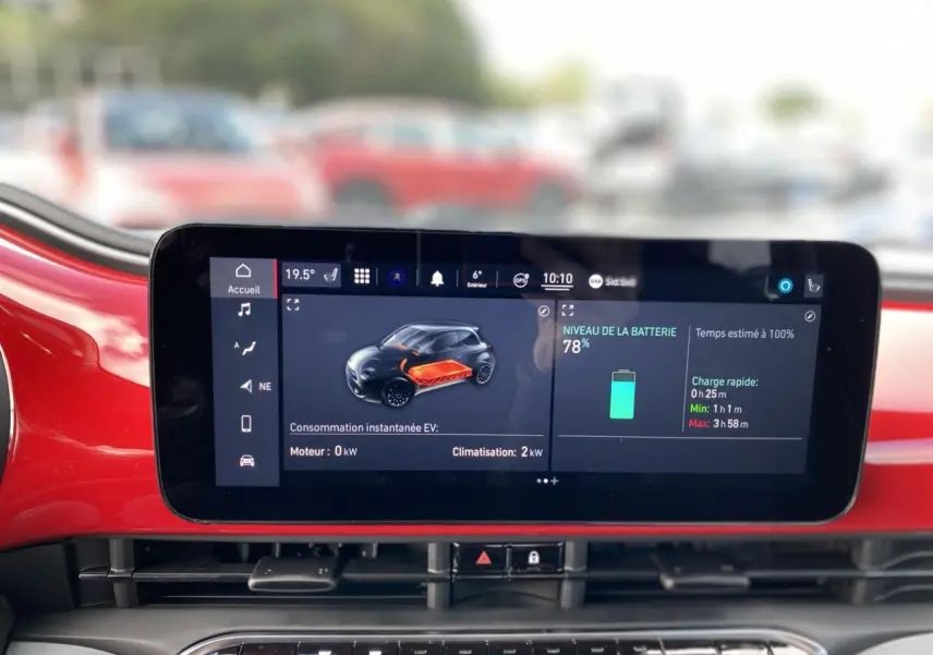 Écran tactile central affichant l'état de batterie et consommation sur fond intérieur rouge vif d'une Fiat 500 Cabriolet Electrique.