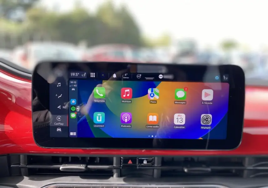 Écran tactile central affichant Apple CarPlay dans l’habitacle rouge vif d’une Fiat 500 Cabriolet électrique.