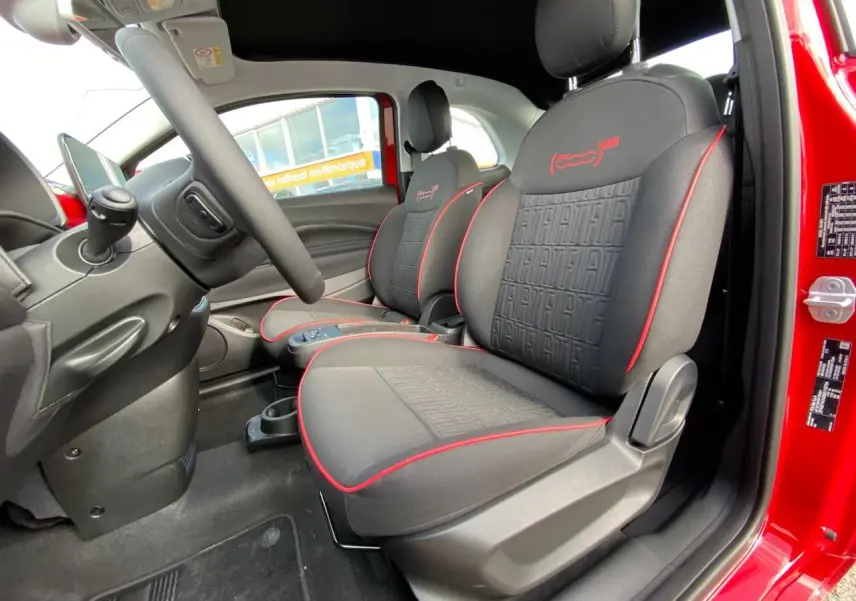 Intérieur côté conducteur du Fiat 500 Cabriolet Electrique rouge, sièges noirs avec surpiqûres rouges et logo 500 RED brodé.