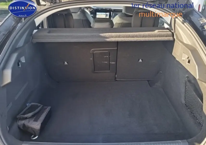 Vue intérieure du coffre noir ouvert du Peugeot 408 Hybrid 145 allure e-dcs6, avec banquette arrière et cache-bagages visibles.