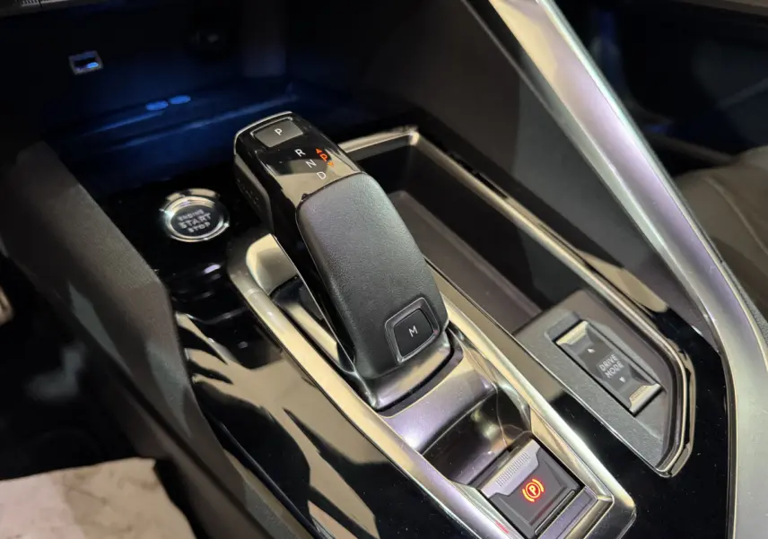 Gros plan sur la commande de boîte automatique noire et le bouton start/stop dans l’habitacle du Peugeot 3008 gris clair.