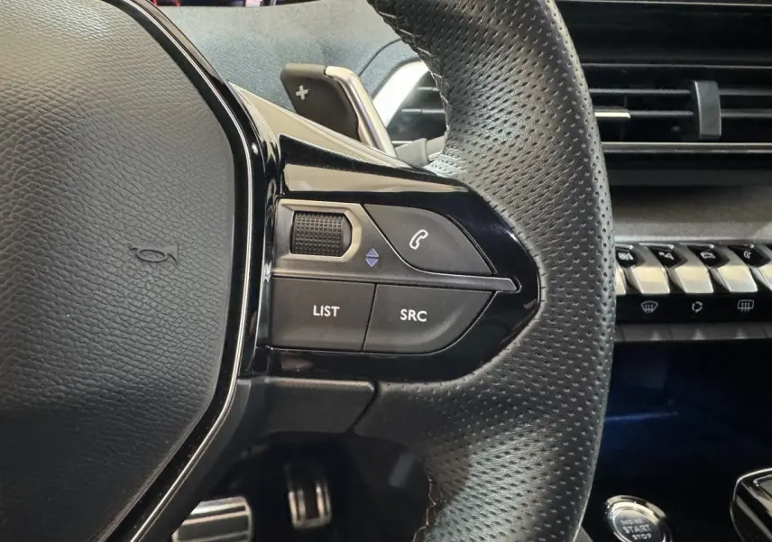 Gros plan sur le volant cuir perforé côté gauche du Peugeot 3008 GT 2021 avec commandes audio et bouton démarrage.