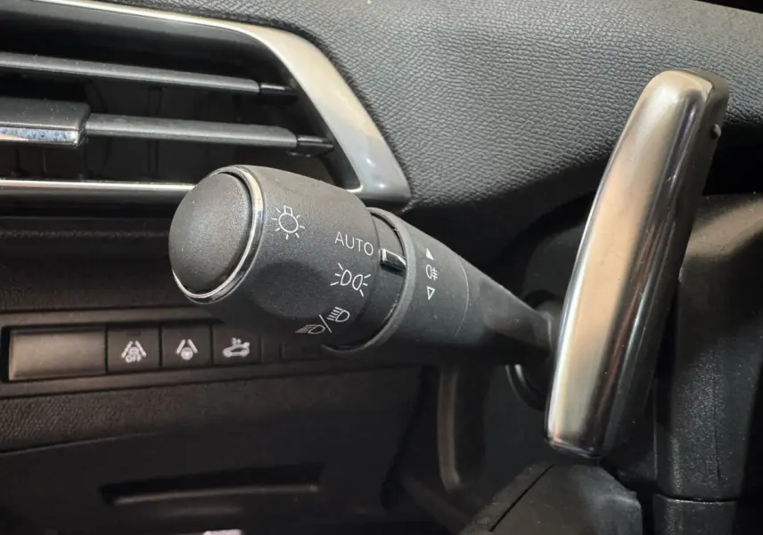 Gros plan sur la commande des phares et clignotants à gauche du volant dans l’habitacle du Peugeot 3008 gris clair.