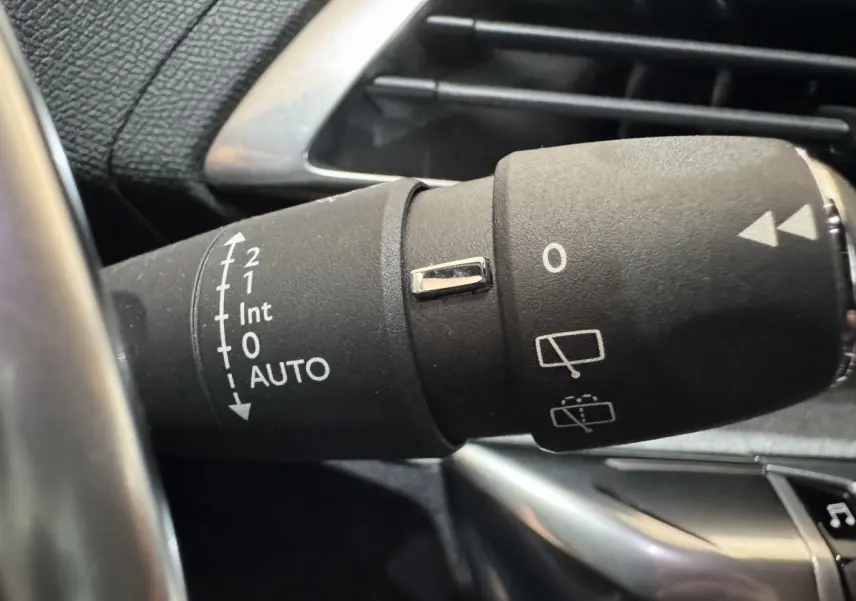 Gros plan sur la commande des essuie-glaces du Peugeot 3008 gris clair, avec marquages blancs et bouton chromé.
