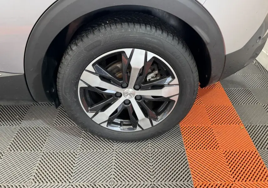 Gros plan sur la roue avant droite gris clair du Peugeot 3008 avec jante alliage bicolore moderne.