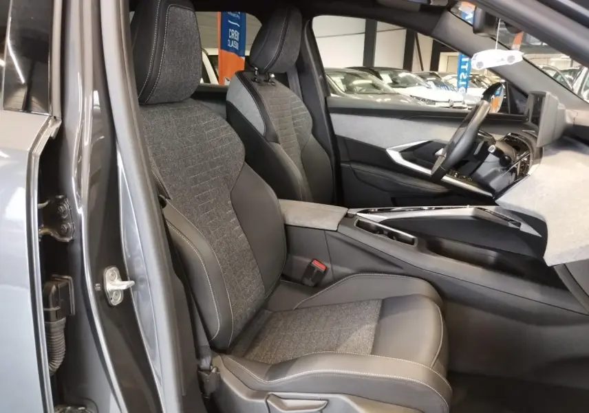 Vue intérieure côté gauche du Peugeot 5008 gris titanium, mettant en valeur les sièges tissu et cuir avec surpiqûres contrastées.