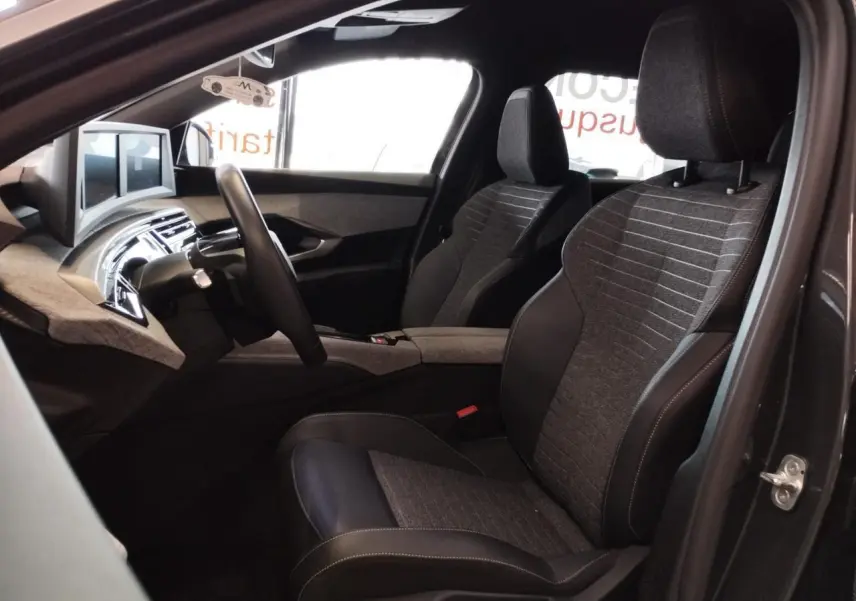 Intérieur avant droit du Peugeot 5008 2025 gris titanium, sièges tissu et cuir avec planche de bord moderne.
